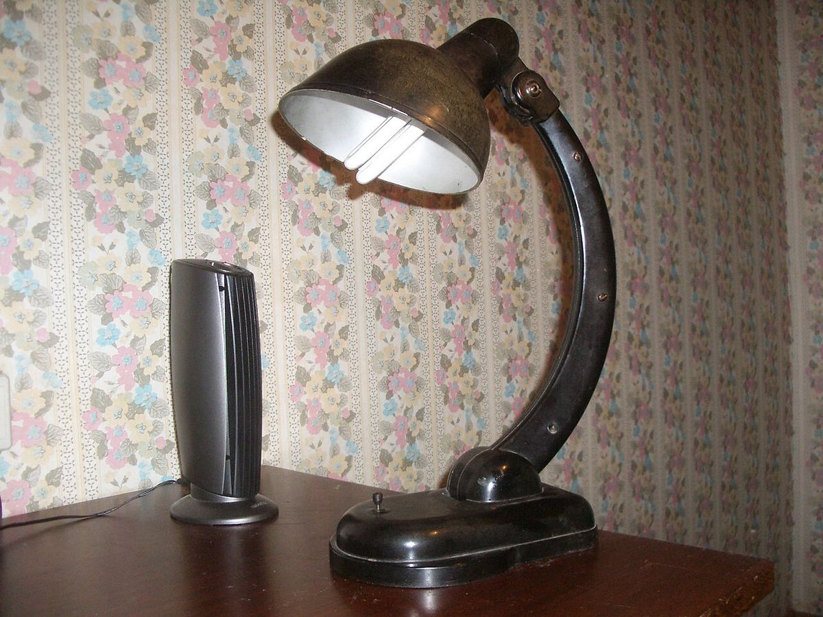 Stará kovová stolná lampa s ramenom na drevenom stole